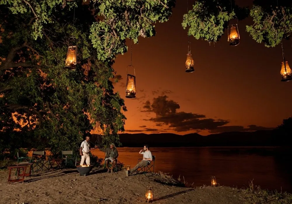 people-sitting-by-the-river-around-a-fire-on-a-safari-in-zimbabwe